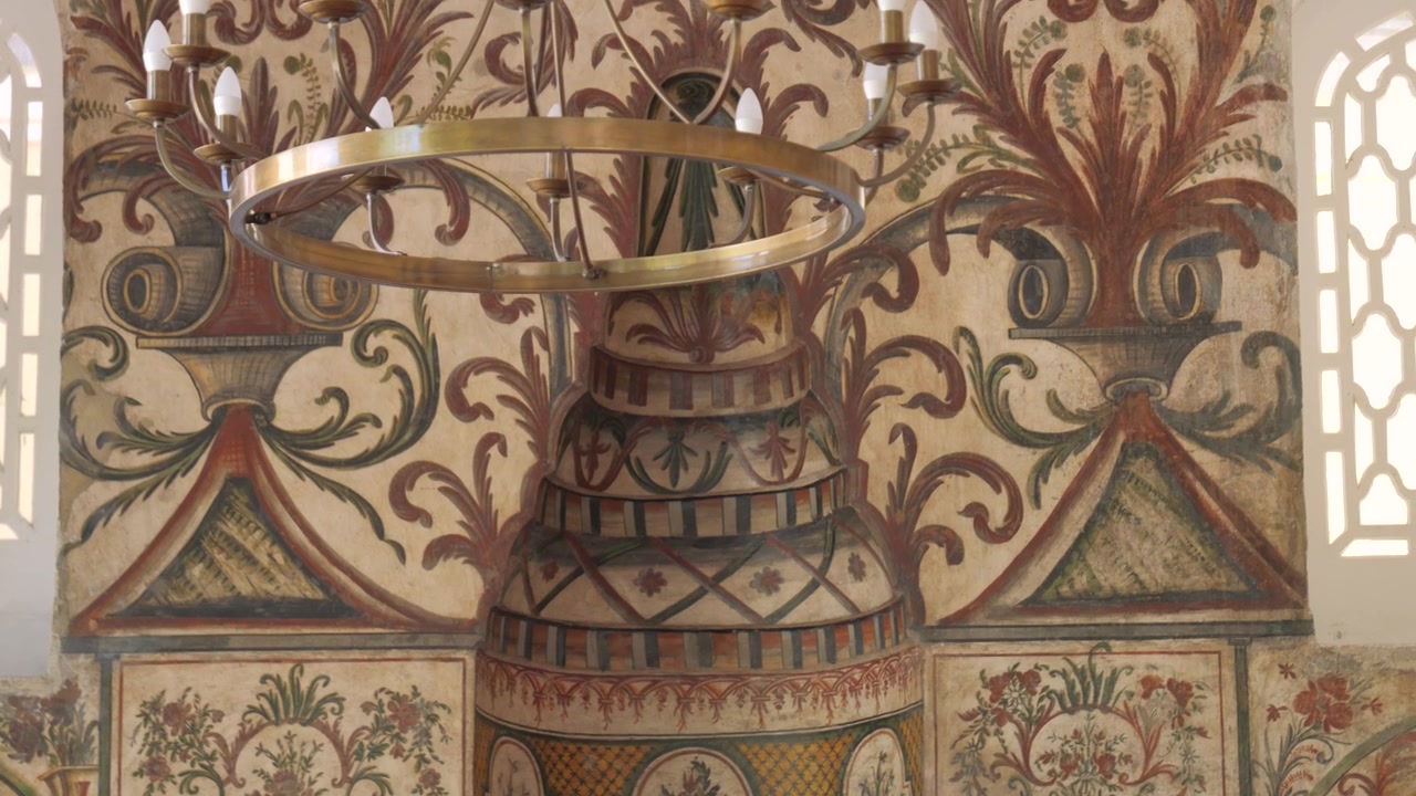 Ornate floral wall paintings and a vintage pendulum clock inside Et'hem Bej Mosque with slow camera move