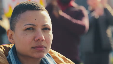 portrait of female protestor in wheelchair surrounded by marchers with placard on demonstration