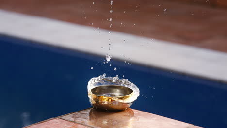 water slashing in a small golden bowel at the edge of a pool