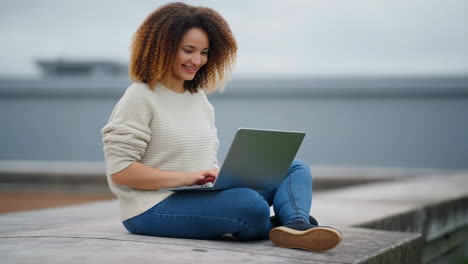 smiling young woman working on laptop outdoors