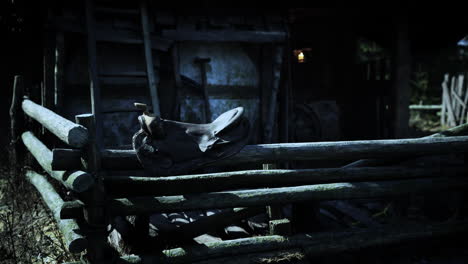 old motorcycle resting on a rustic wooden fence near an abandoned barn at dusk