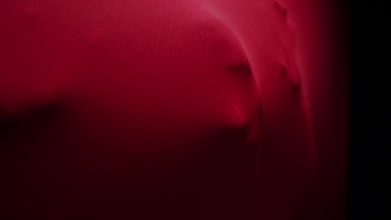 Mani e viso che spuntano da un tessuto rosso in modo inquietante
