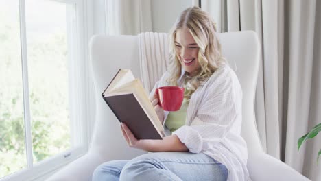 Retrato-De-Una-Mujer-Caucásica-Feliz-De-Talla-Grande-Leyendo-Un-Libro-Y-Tomando-Café