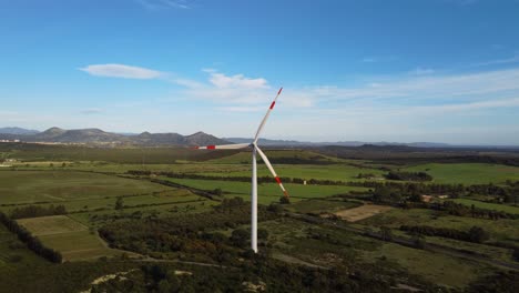 4k aerial of wind turbine, wind spinning red stripped blades in rural landscape