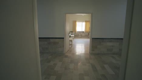 pov of minimal hospital room with beds and open doors leading to another room space.