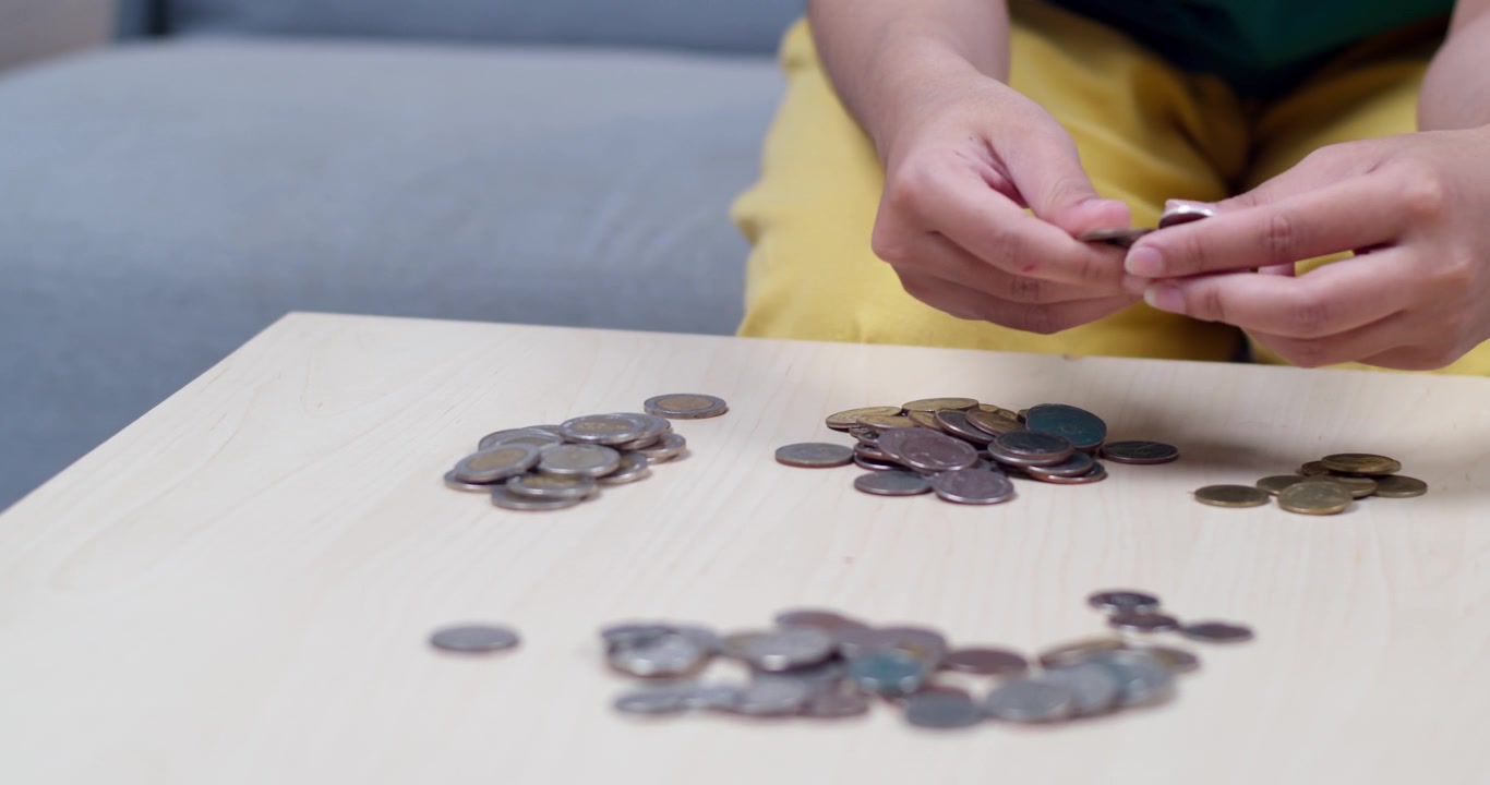 Una persona conta meticolosamente le monete su un tavolo per gestire efficacemente le finanze personali