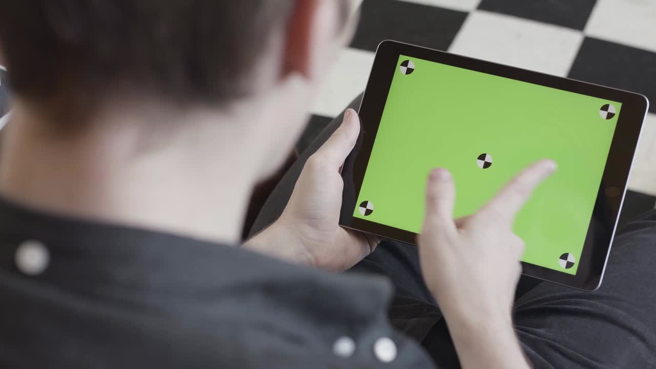 녹색 화면을 가진 태블릿을 사용하는 사람
