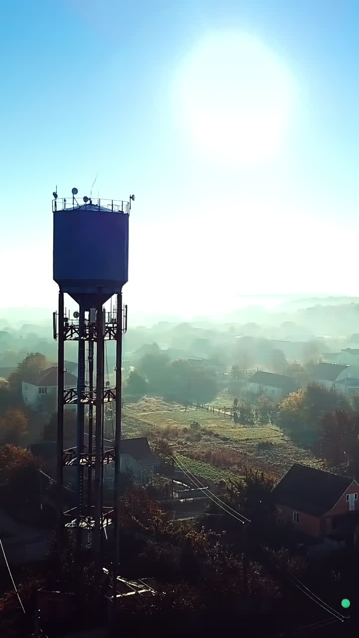 Dron shot aerial over the countryside and the big steel tower at sunrise. High metal construction in the rural place in the morning dawn. Camera moves left. Vertical video