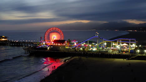 santa monica pier at night with illuminated ferris wheel and roller coaster