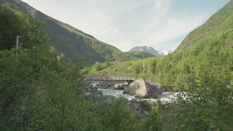 一名徒步旅行者和一只狗在挪威lyngsdalen山谷的河流中穿过桥梁 - - 广泛拍摄