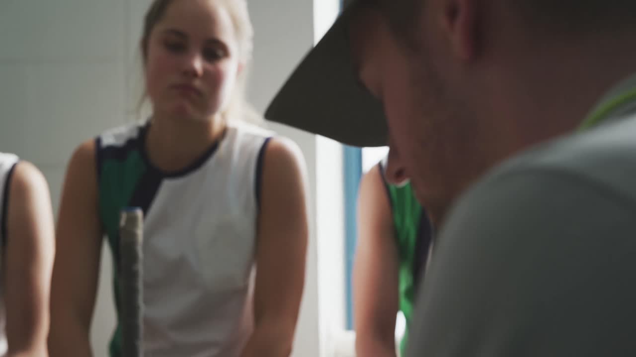 entrenador de hockey hablando con jugadoras en el vestuario