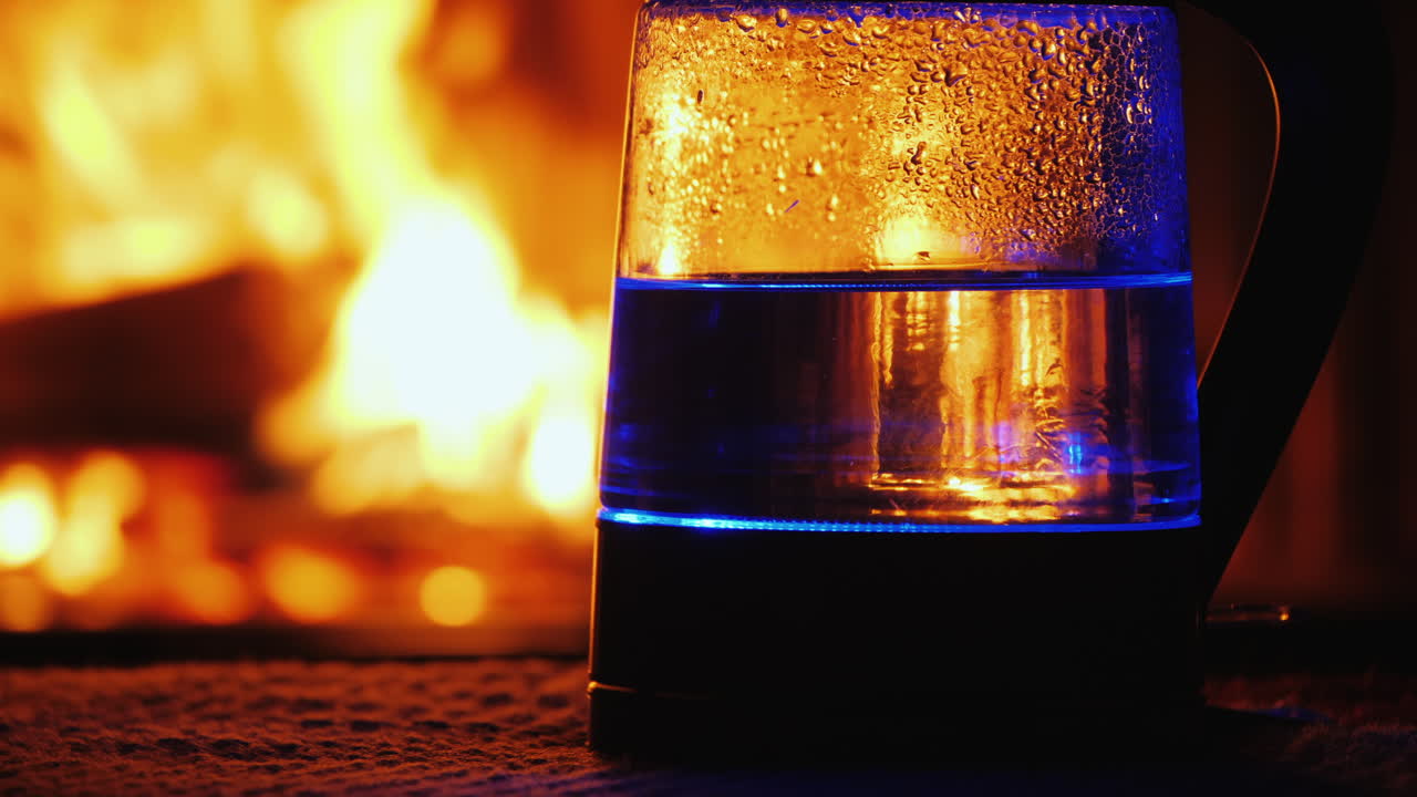 el agua hierve en un hervidor eléctrico retroiluminado un fuego en el fondo arde en el fondo