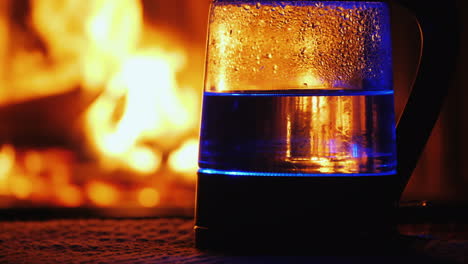 Water-Boils-In-A-Backlit-Electric-Kettle-A-Fire-In-The-Background-Burns-In-The-Background