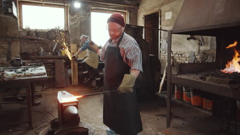 two blacksmiths using hammer and cutting wheel in workshop