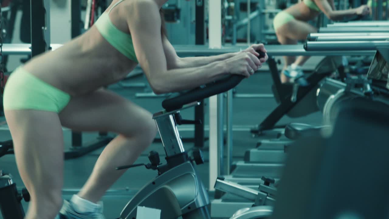 Athletic Woman With Headphones Pedaling On The