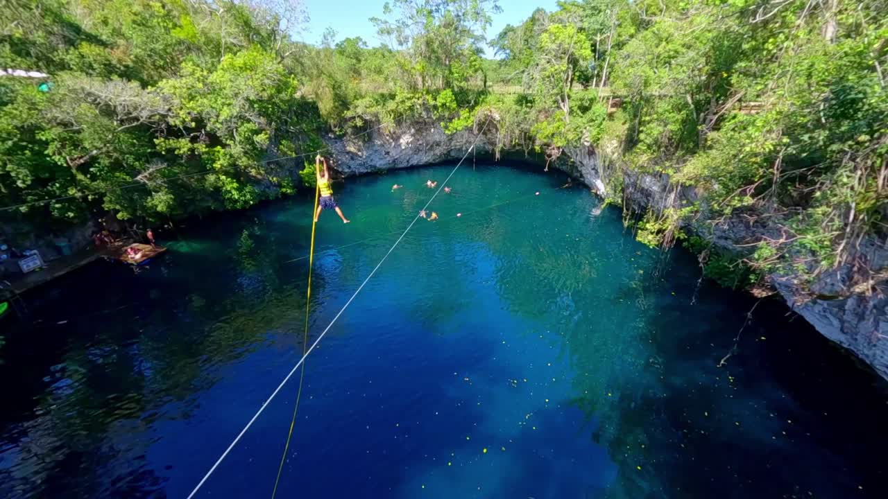 Vista da drone FPV di un uomo che fa zipline e si tuffa nella laguna blu Dudu, La Entrada