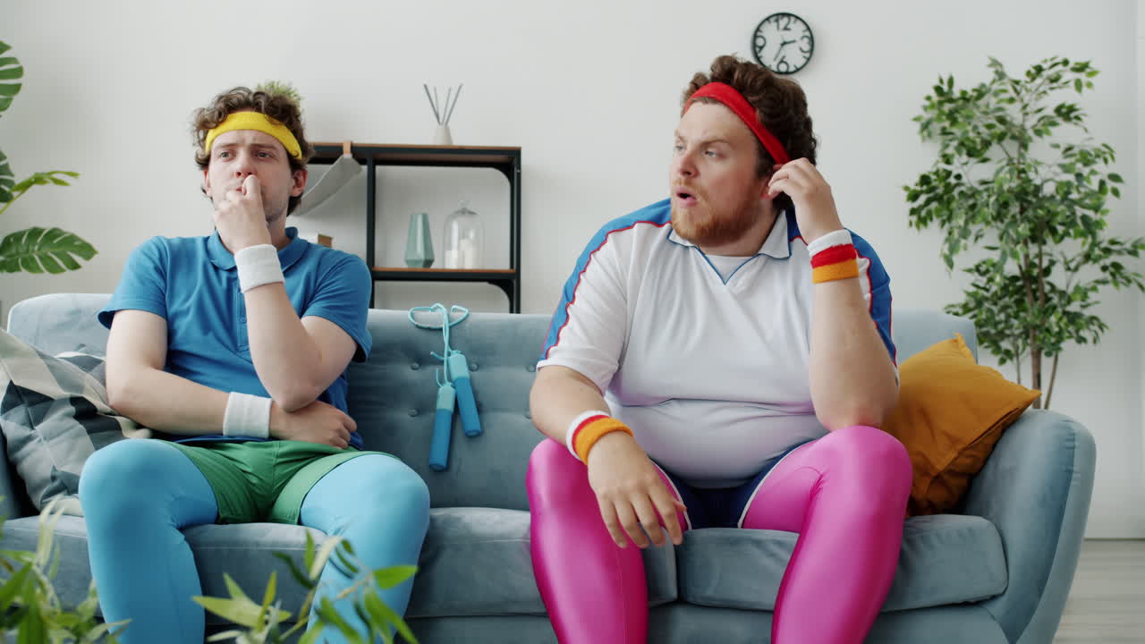 Two Men in Retro Sportswear Arguing on a Couch