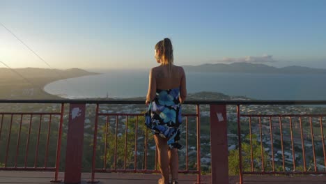 woman in floral tube dress at viewing platform of castle hill lookout in townsville, queensland, australia