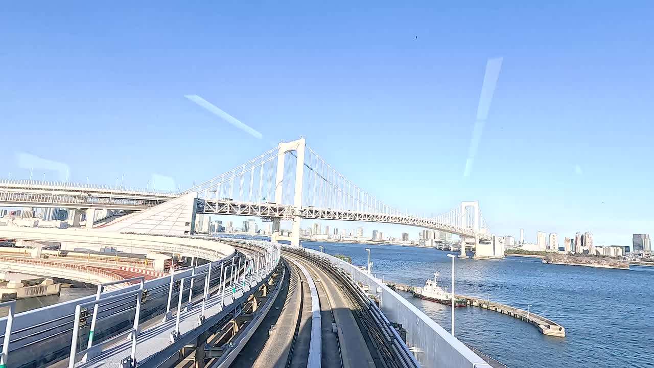 A train travels smoothly over Tokyo Bay Bridge, offering stunning views of the city skyline and waterfront