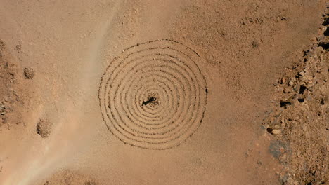 aerial: rising top down shot of one man standing in the middle of a spiral rock formation