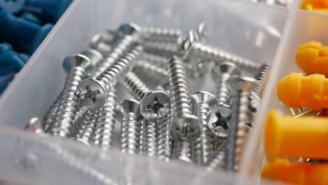 varios tornillos, clavos y tapones de pared en una caja de almacenamiento