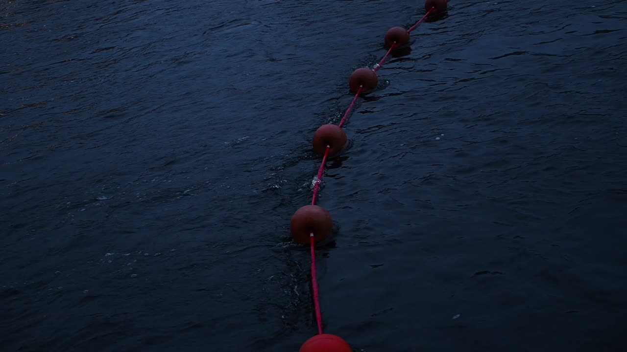 밤에 강에 떠 있는 빨간 부표가 있는 밧줄