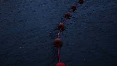 Rope-with-red-buoys-floating-in-the-river-at-night