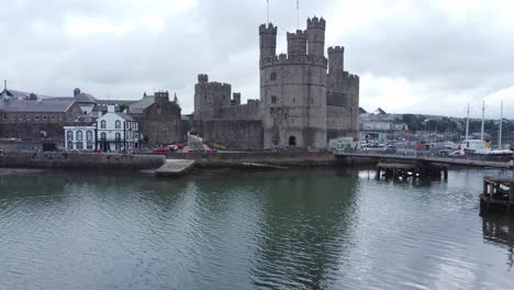 ancient caernarfon castle welsh harbour town aerial view medieval waterfront landmark low left rising shot