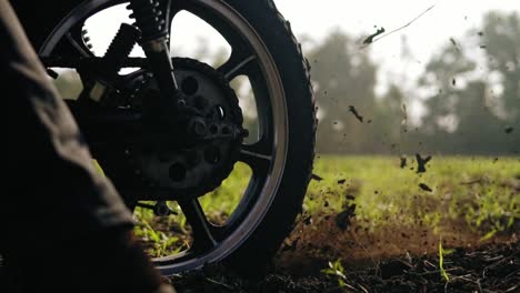 wheel of motorcycle starting to spin and kicking up ground or dirt. motorcycle starts the movement. slow motion