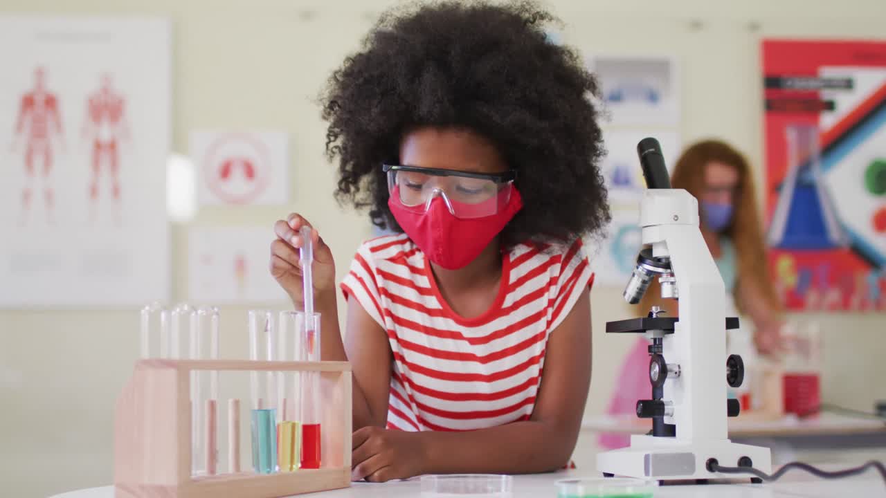 niña con máscara facial y gafas de protección usando pipeta y tubos de ensayo en el laboratorio