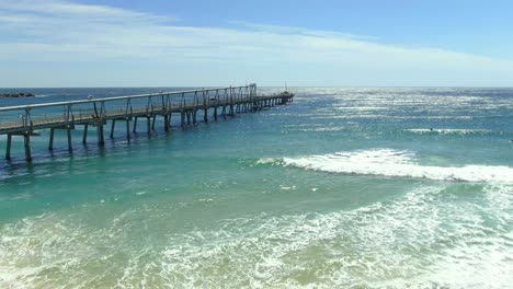 Jetty-extending-out-across-crashing-waves-on-a-beautiful-summers-day,-Gold-Coast-Spit
