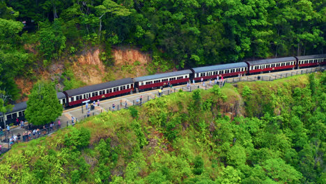 aerial view of kuranda scenic railway train stops at barron gorge national park with tourists admiring the lush rainforest in australia