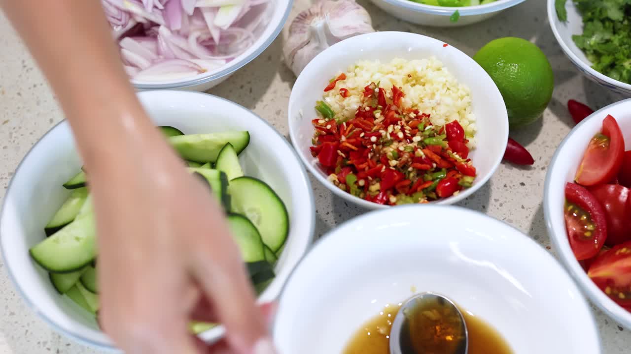Hands prepare fresh vegetables and herbs for a colorful salad. Bright lighting enhances the vibrant ingredients on a kitchen counter
