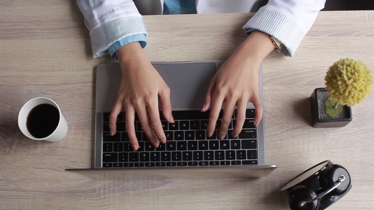 la vista superior de la mujer de negocios está sentada en el escritorio de madera en la oficina escribiendo en el teclado de la computadora portátil, escribe, escribe correos electrónicos, navega por internet