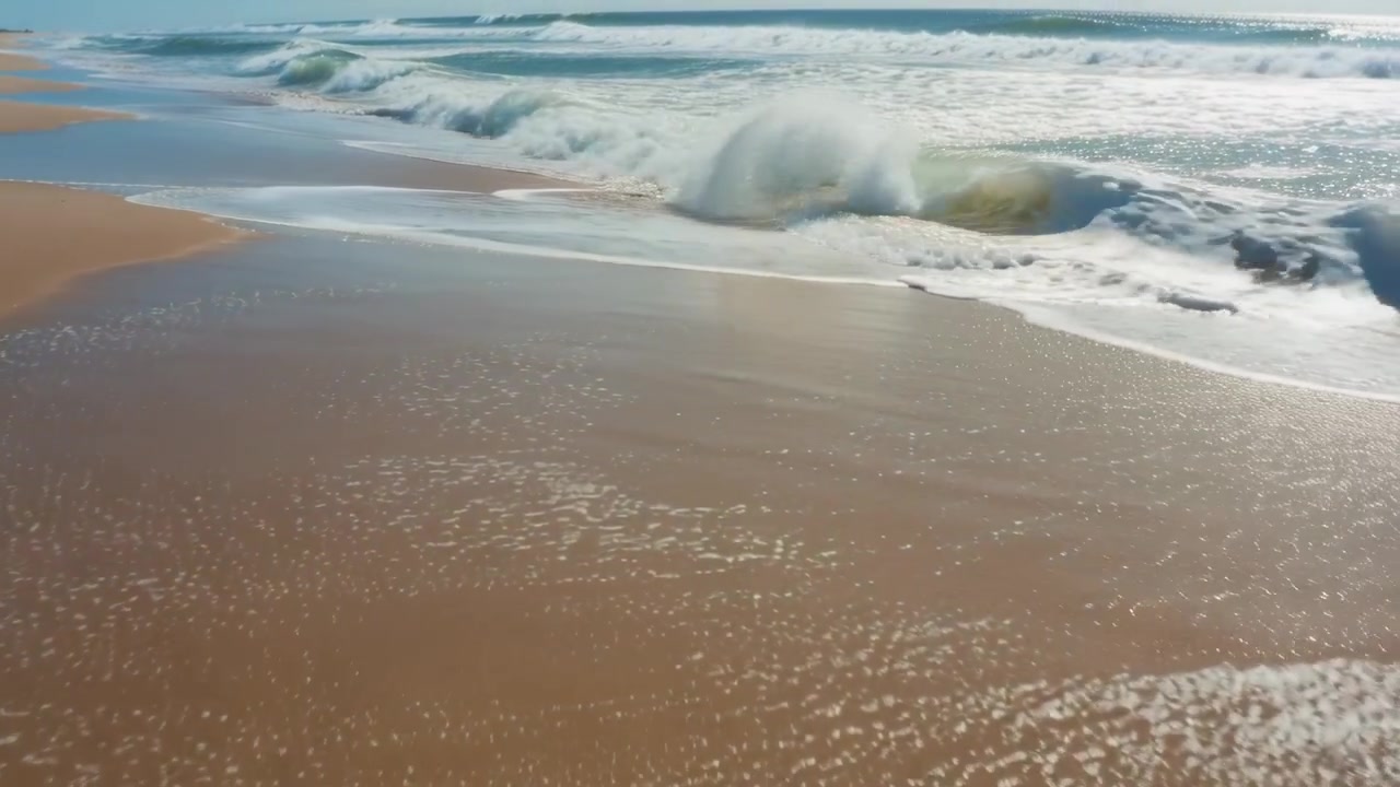 Incoming swell sending crest breaking and retreating at beach leaving white foam