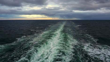 view of ship's wake trailing into a cloudy, golden sunset at sea between prince edward island and la baie