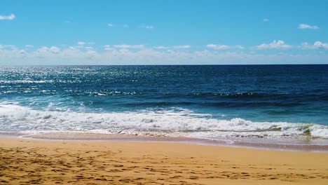 HD-Hawaii-Kauai-slow-motion-beautiful-backlit-shot-of-ocean-waves-breaking-on-beach-in-lower-third,-ocean-in-middle-third,-clouds-at-horizon-and-blue-sky-in-upper-third-version-one