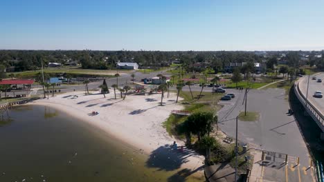 Dropping-drone-view-of-Leslie-Porter-Wayside-Park-and-playground-in-Lynn-Haven-from-Old-Bailey-Bridge-with-birds-flying-towards-camera