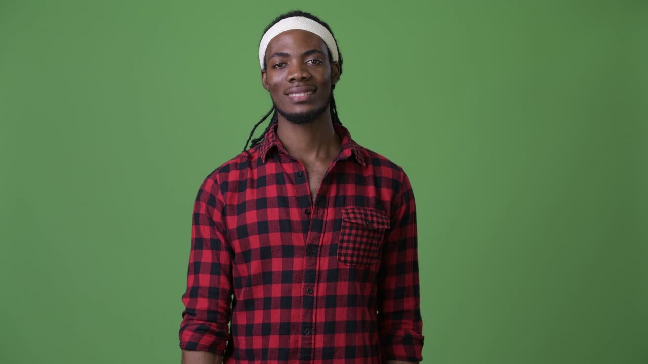 Giovane e affascinante uomo africano con i dreadlock su sfondo verde
