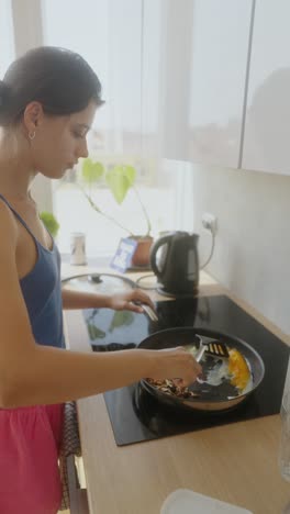young woman cooking eggs in a kitchen