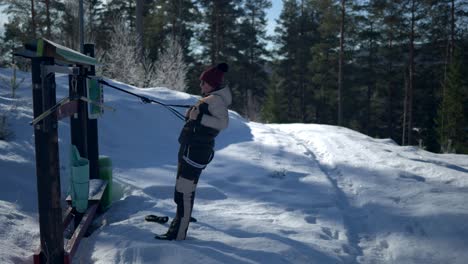 a female doing training at outdoor gym during winter with snow and forest background