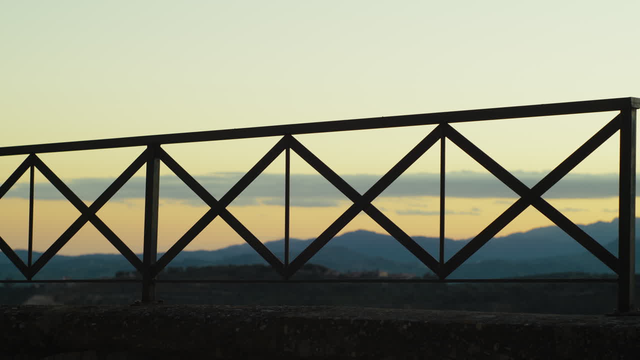 silueta de un balcón mirando hacia las montañas al atardecer