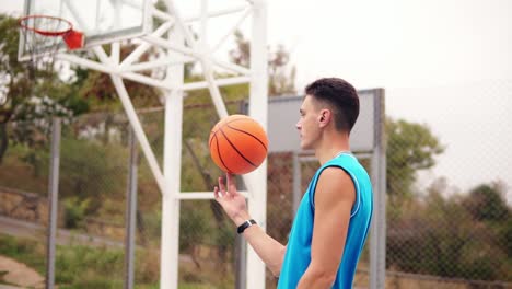 portrait of a basketball player spinning a basketball on the street playground. slow motion shot