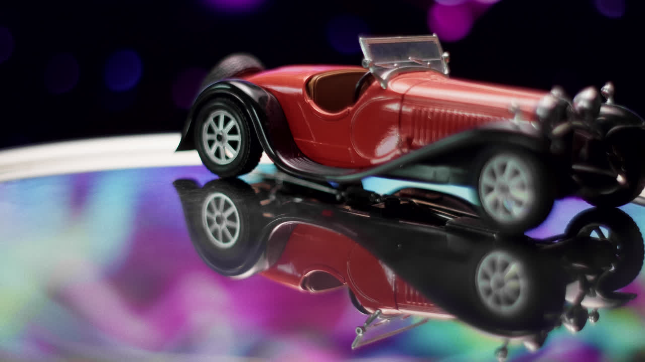 Red Vintage Model Car on Reflective Surface with Bokeh Background