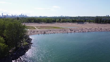 view from a drone flying near a sunny toronto beach with many beachgoers on lake ontario