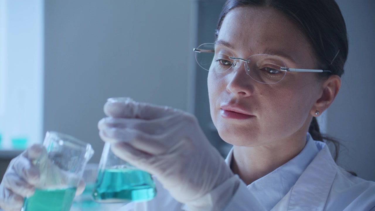 Female Scientist Pouring Chemical Liquid into Laboratory Flask during Research