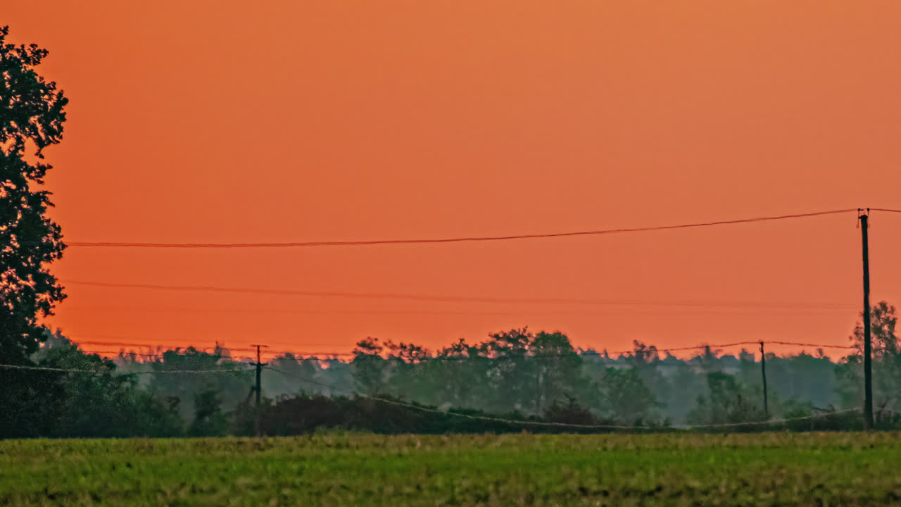 Giant sun close-up. Sun rising over field with vibrant red and orange sky. Timelapse