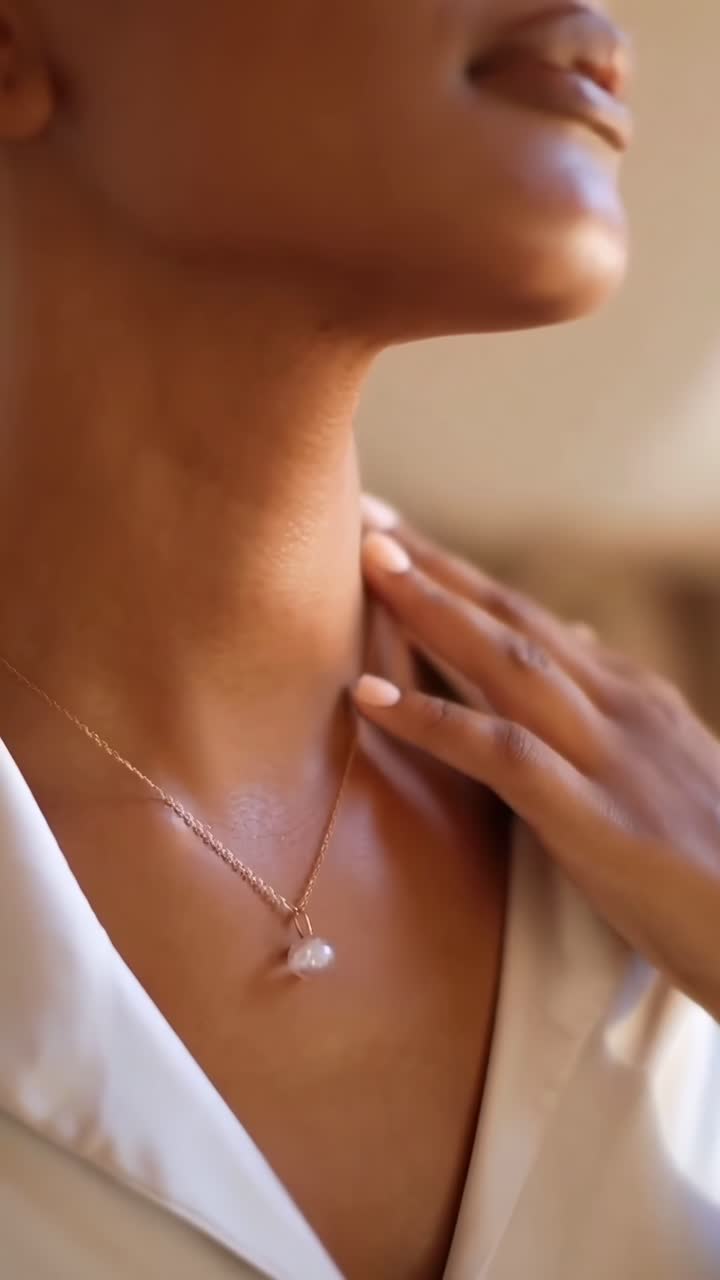 Angolazione video ravvicinata di una donna che indossa una collana, che mette in risalto eleganza e illuminazione soffusa