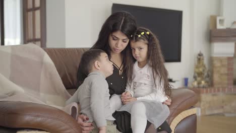 attractive middle eastern woman sitting on the coach with two little children