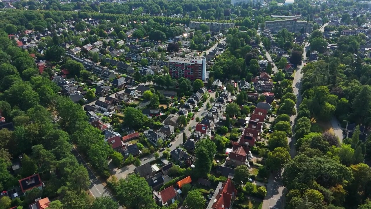 Luchtfoto van een groene woonwijk in Apeldoorn, Nederland, met huizen, bomenrijke wegen, appartementencomplexen, tuinen en een duurzame stedelijke indeling.